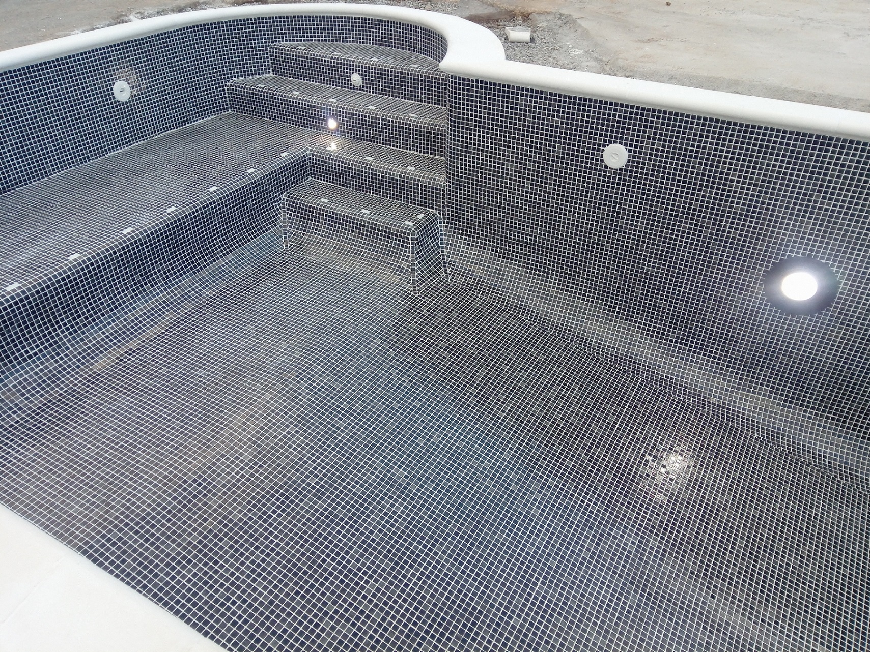 Pool interior with dark mosaic tiles and step lighting