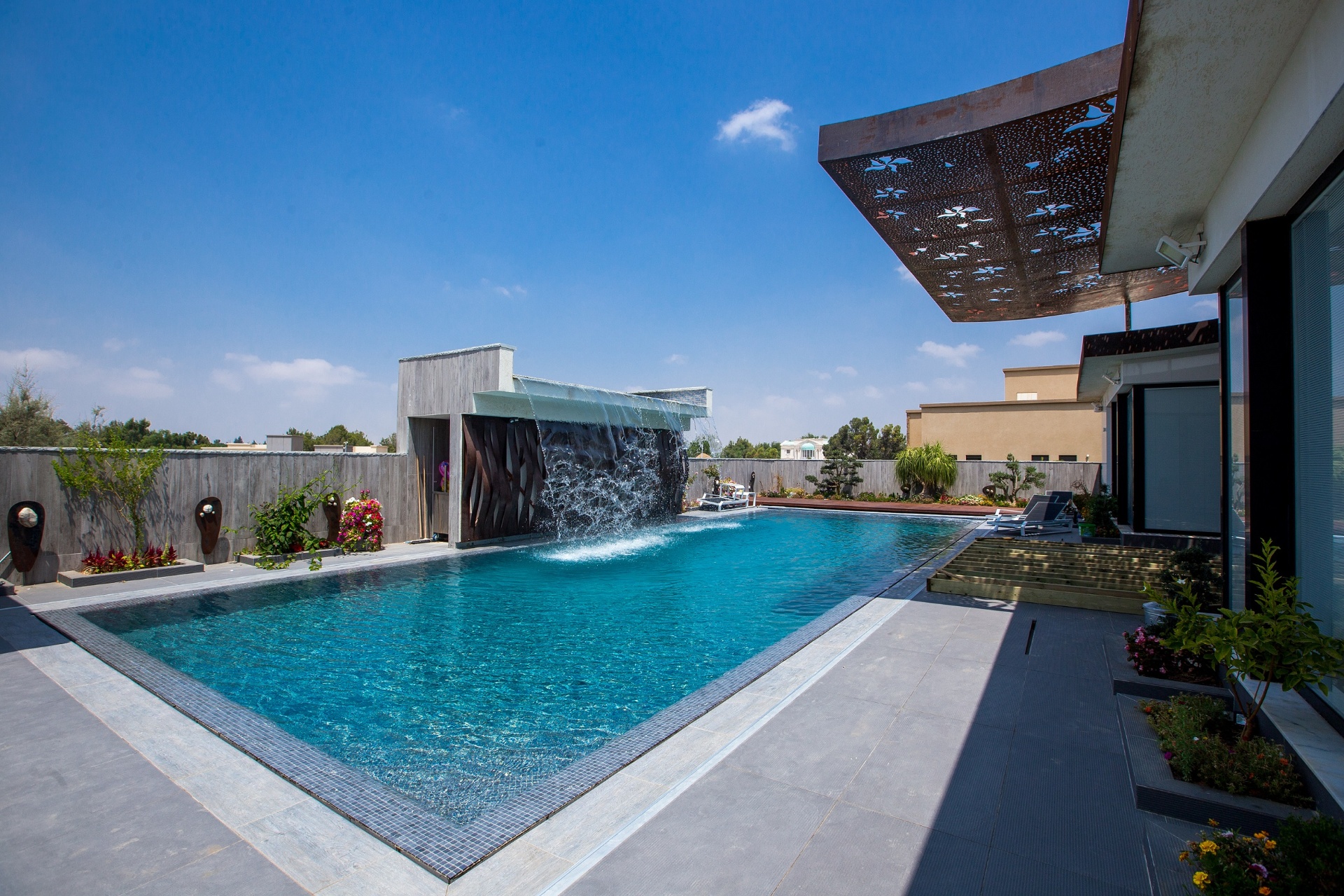Luxury pool with waterfall feature and mosaic interior