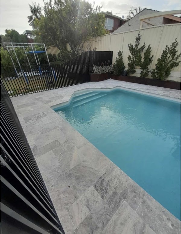 Fibreglass pool with travertine paving and modern black fencing